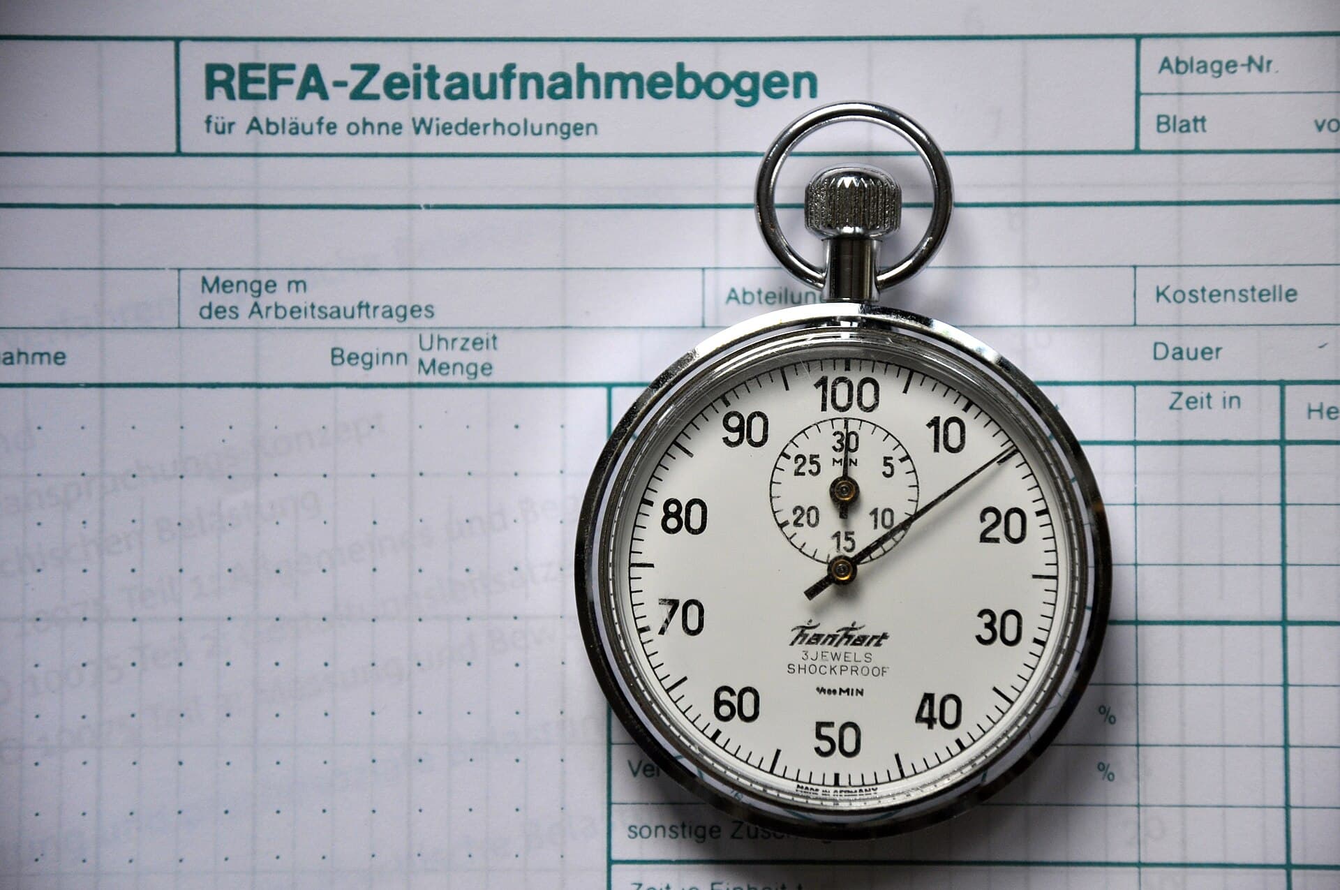 A mechanical stopwatch lying on a printed time-study form